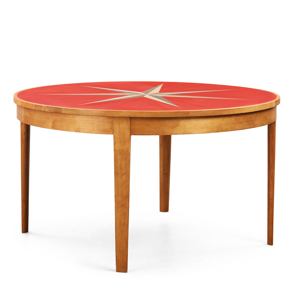 Ett runt matbord i trä från 1936 med röd toppskiva.